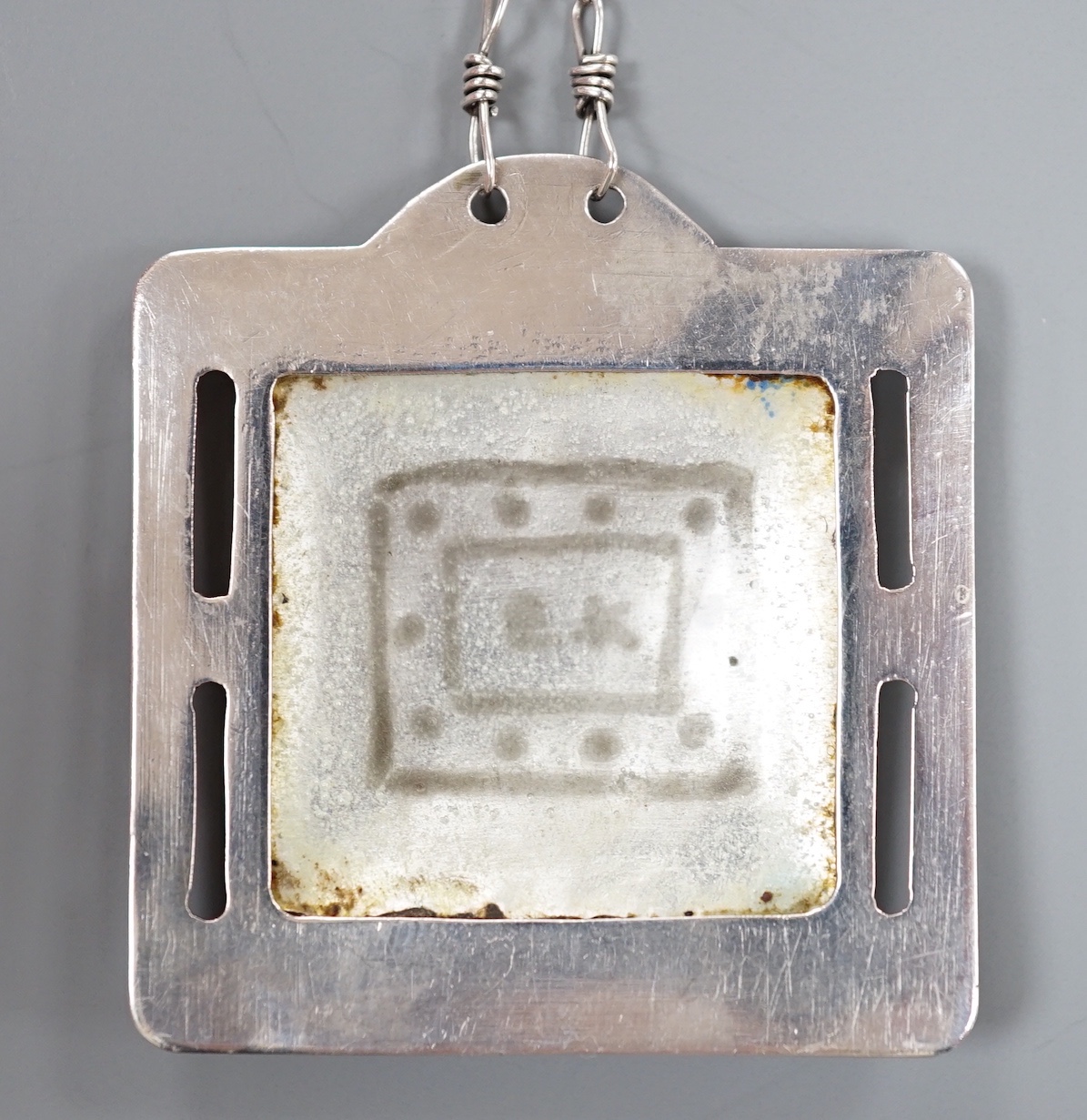 A continental white metal and polychrome enamel square pendant on chain, pendant 42mm, maker EK?.